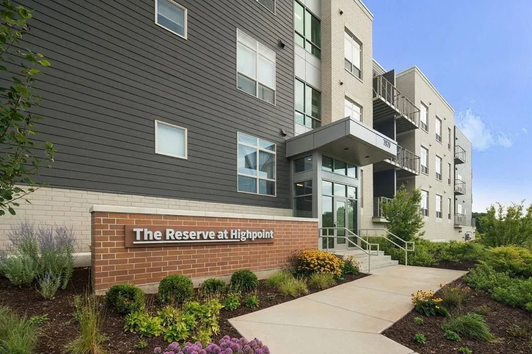 Apartment building entrance with masonry, siding and landscaped grounds