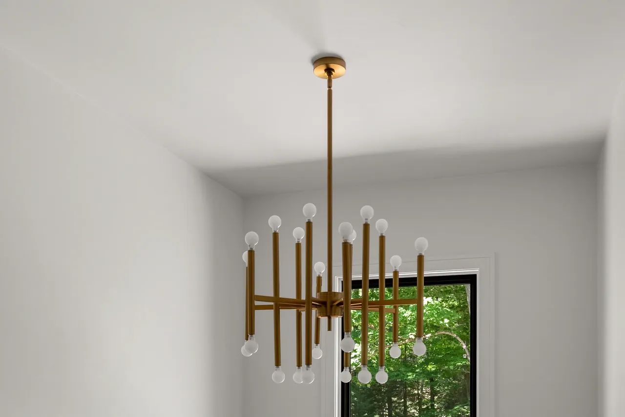 Brass chandelier framed by a pale ceiling and a black window