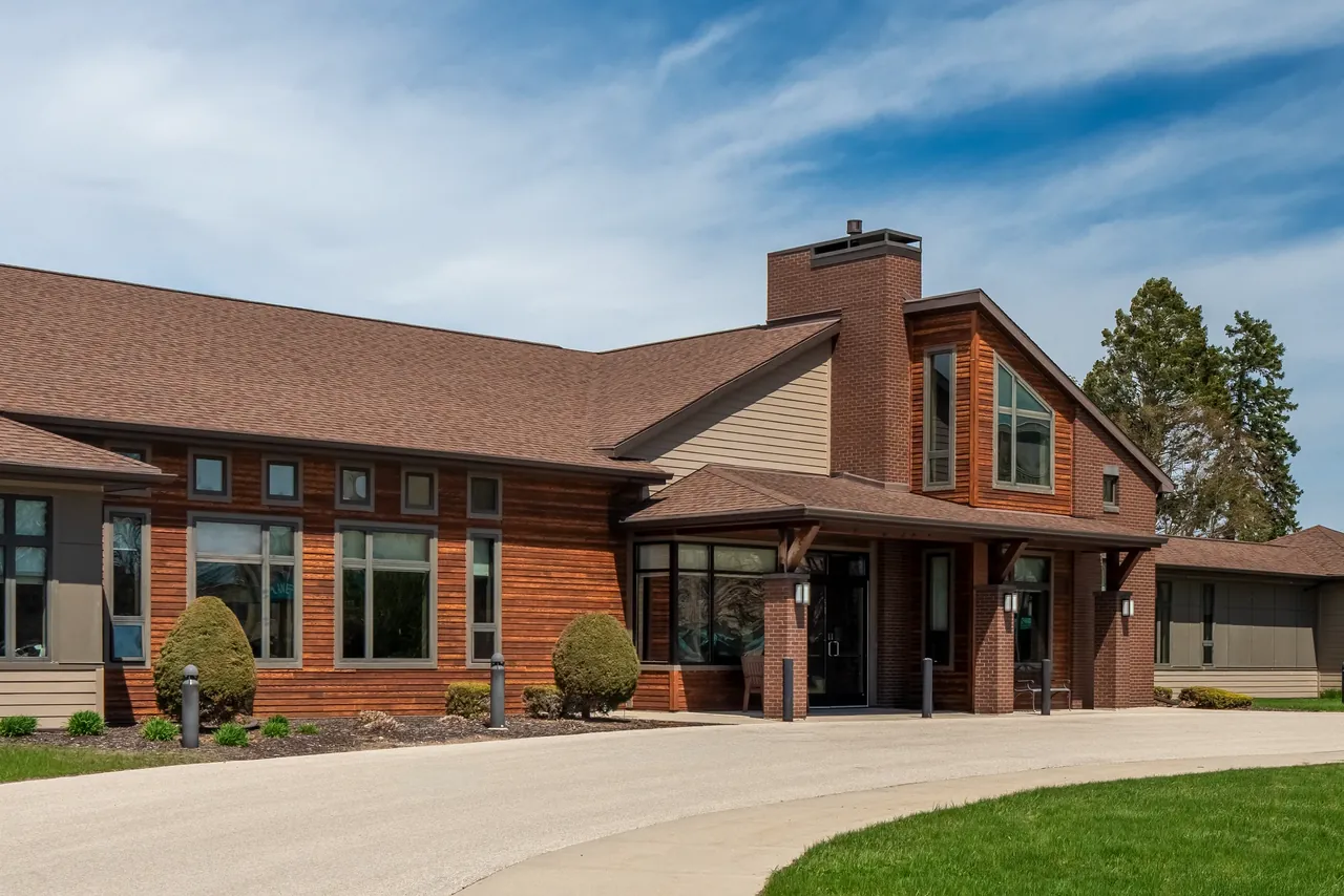 Low brick building with a pitched roof, landscaped entry and lawn