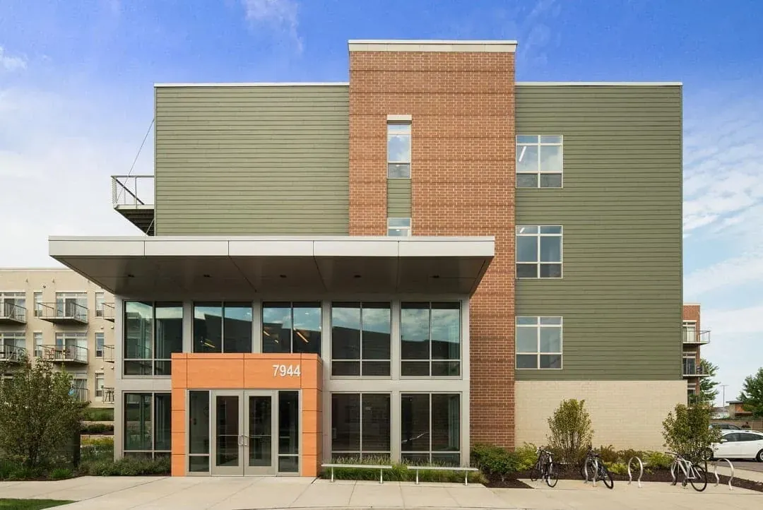 Commercial building with a glass entrance and green and brick exterior