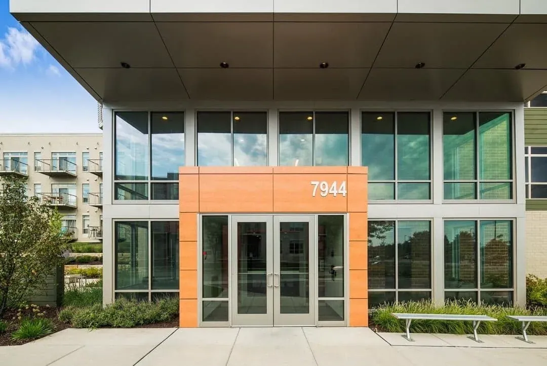 Modern commercial entry with tall glass panels and a wood accent facade