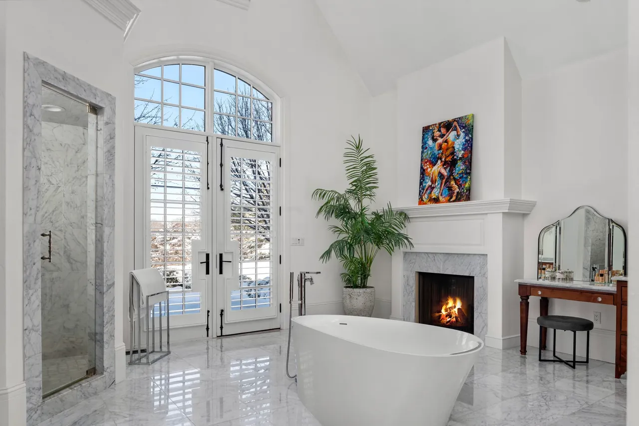 Double-height interior with a white fireplace, tall windows and colorful artwork