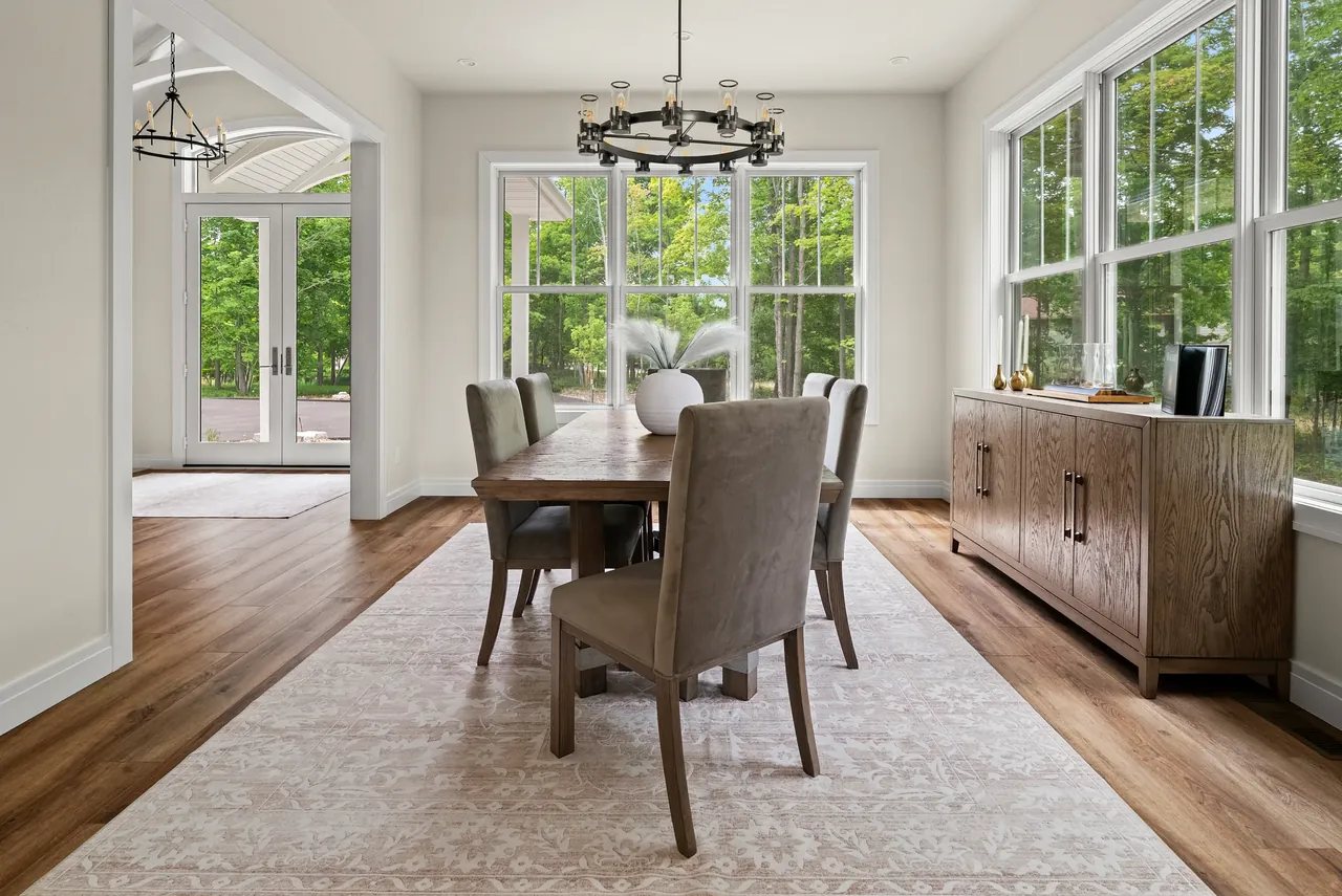 Dining room with a wood table, pale upholstered chairs and tall windows
