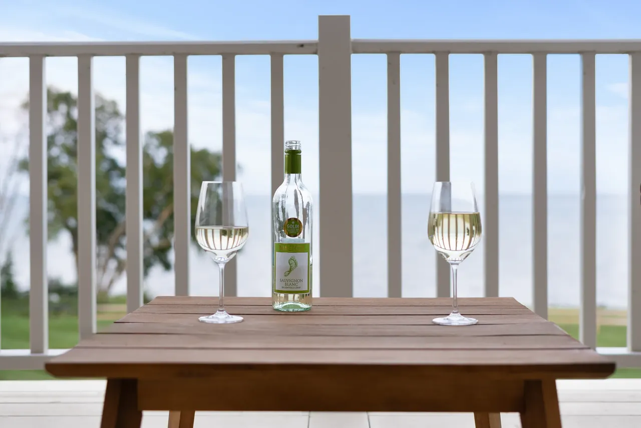 Wood dining table with glass vessels in front of bright windows