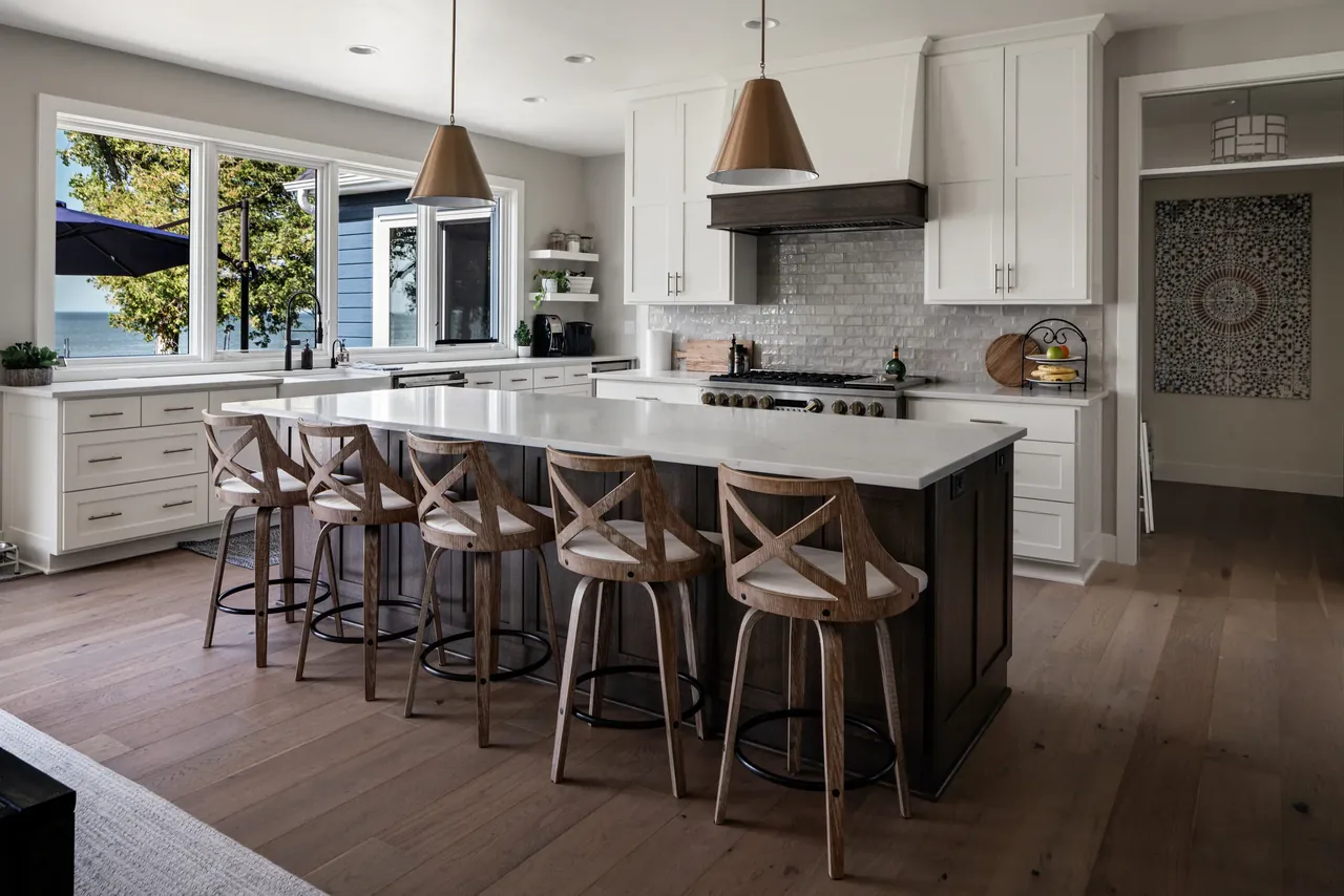 Kitchen island with dark stools, pendant lighting and white cabinetry