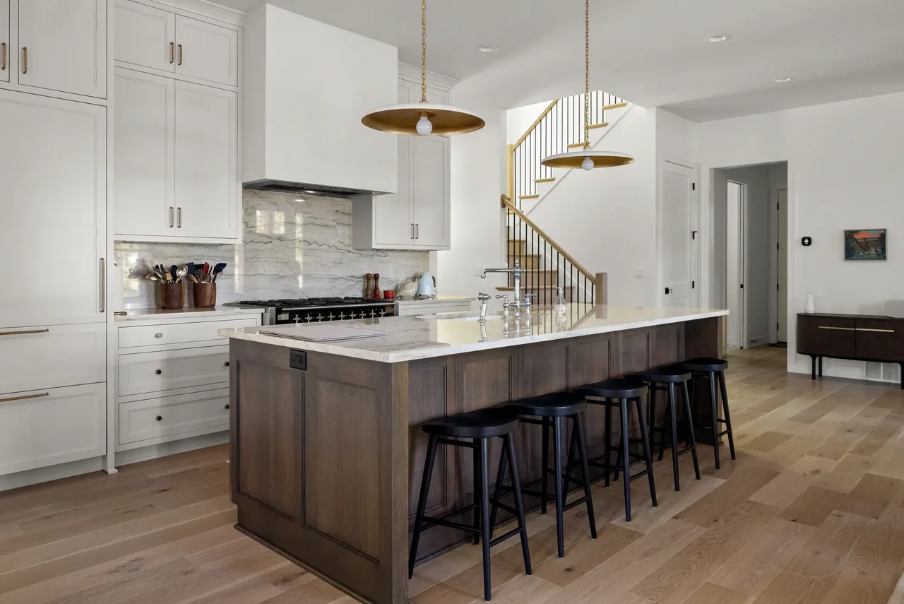 Kitchen with a broad wood island, pendant lights and pale cabinets