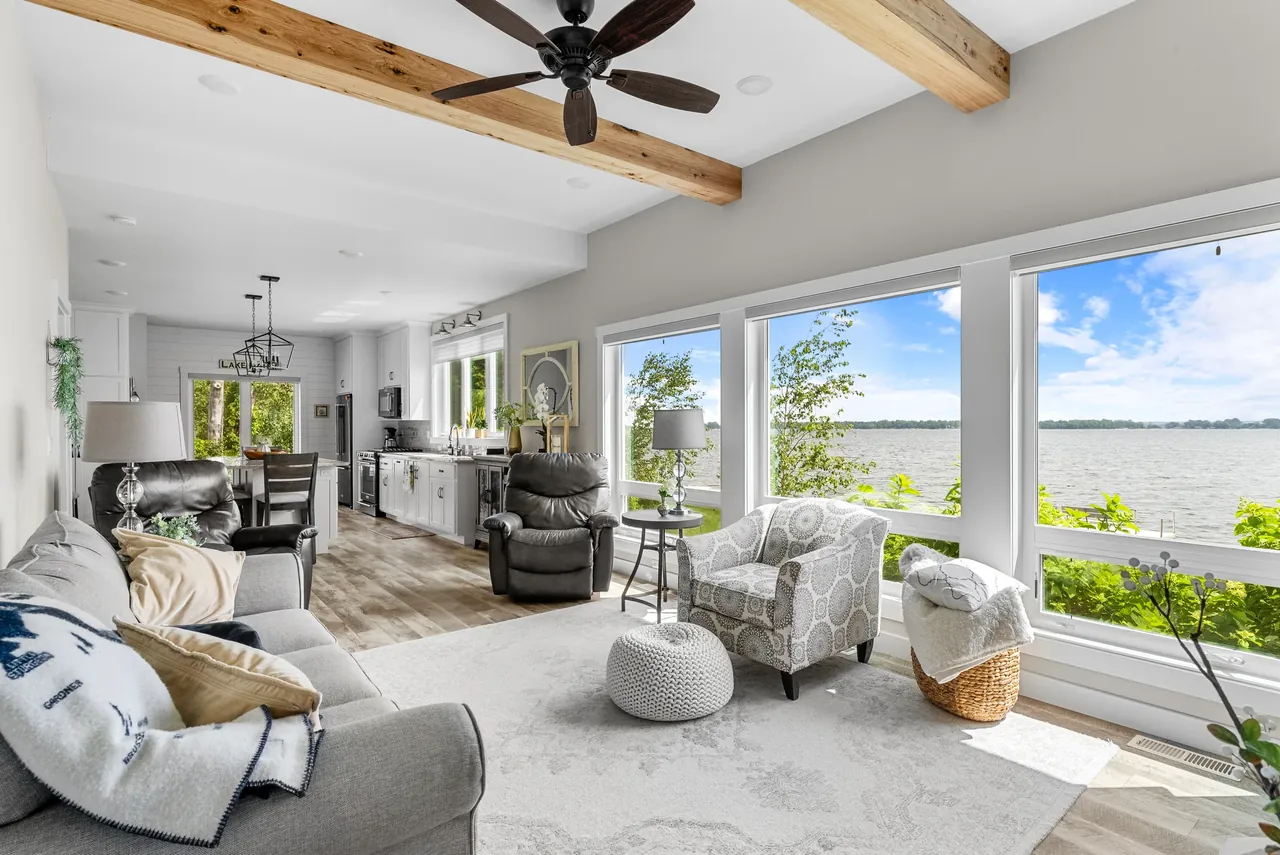 Bright living room with a ceiling fan and wide windows facing the water