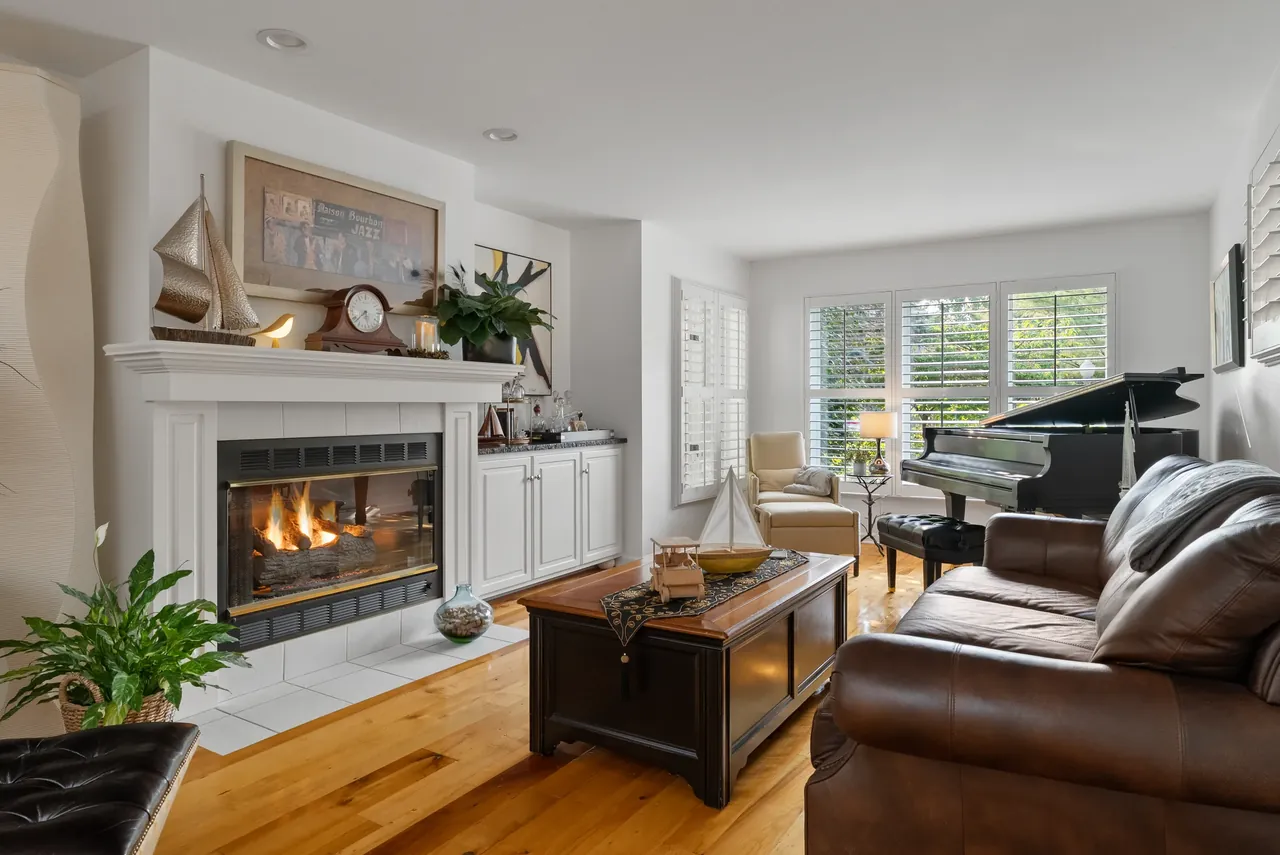 Living room with leather seating, a fireplace and windows overlooking the yard
