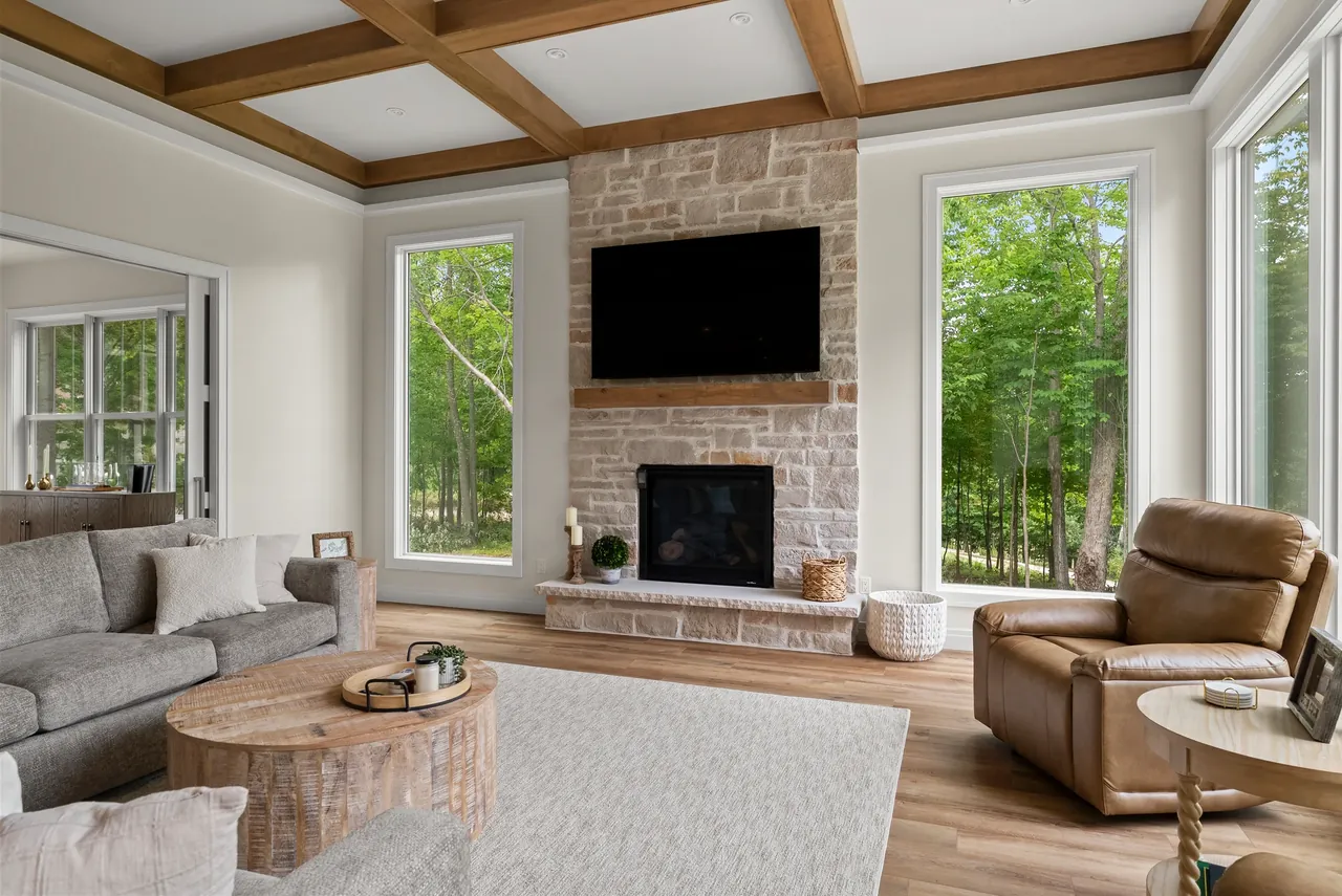 Living room with a fireplace, wood ceiling beams and large windows