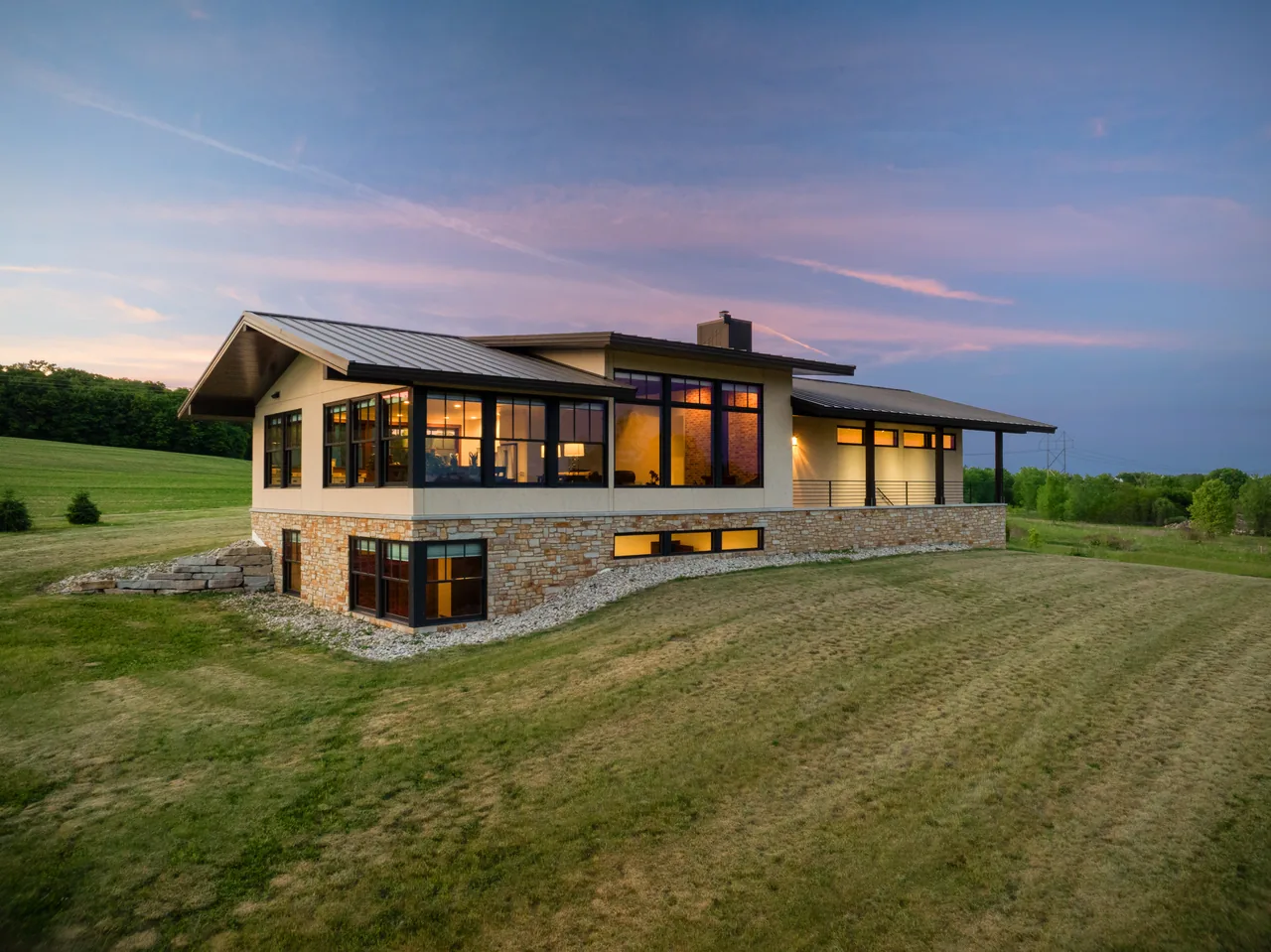 Elevated twilight view of a modern country home with glowing windows