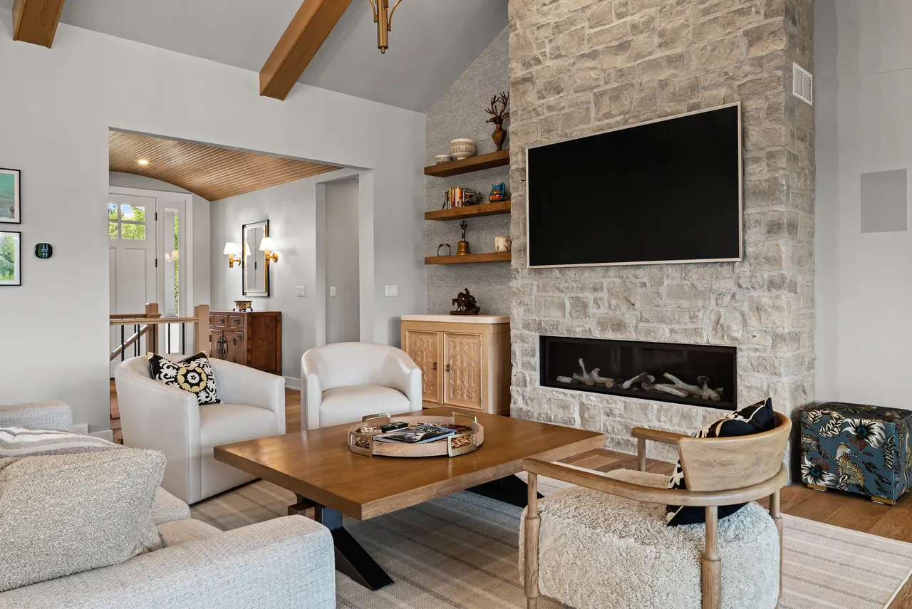 Living space with a stone fireplace, wood shelving and upholstered seating