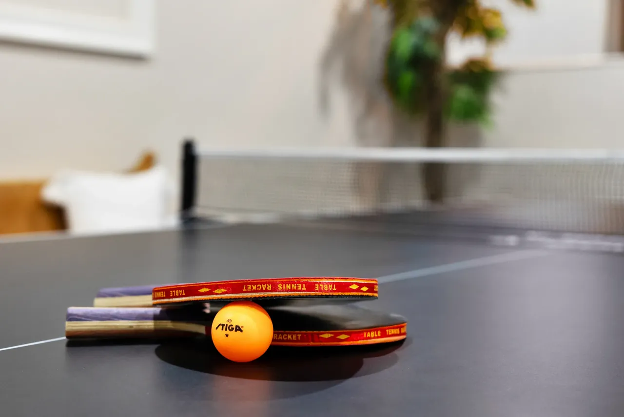 Table tennis paddles and a ball on an indoor game table