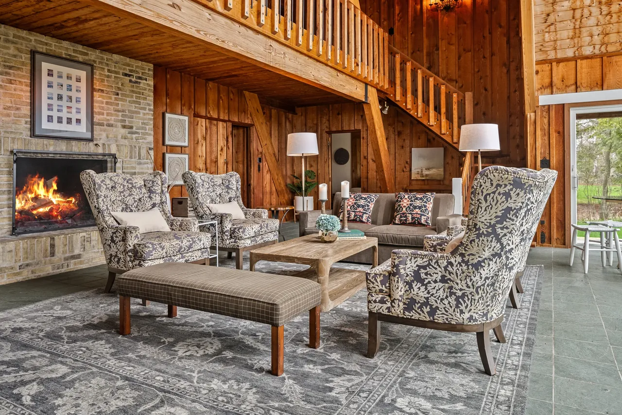 Timber-lined lodge living room with a stone fireplace and patterned armchairs