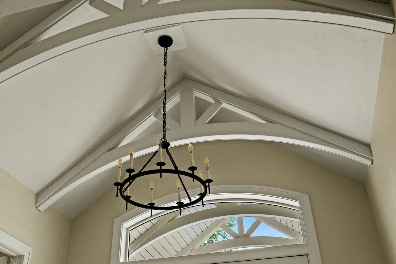 Circular chandelier beneath a vaulted ceiling with timber beams