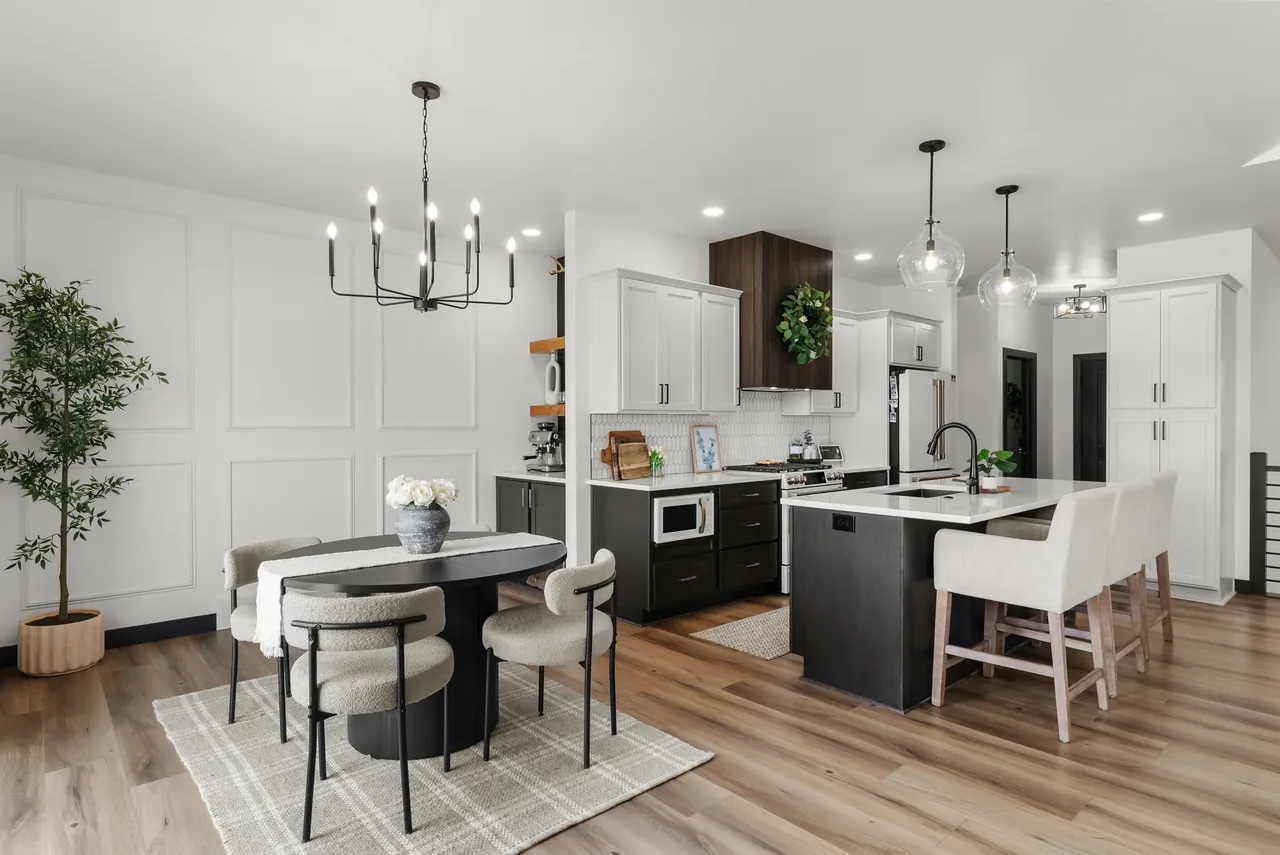White kitchen with a dark island, pendant lighting and upholstered stools