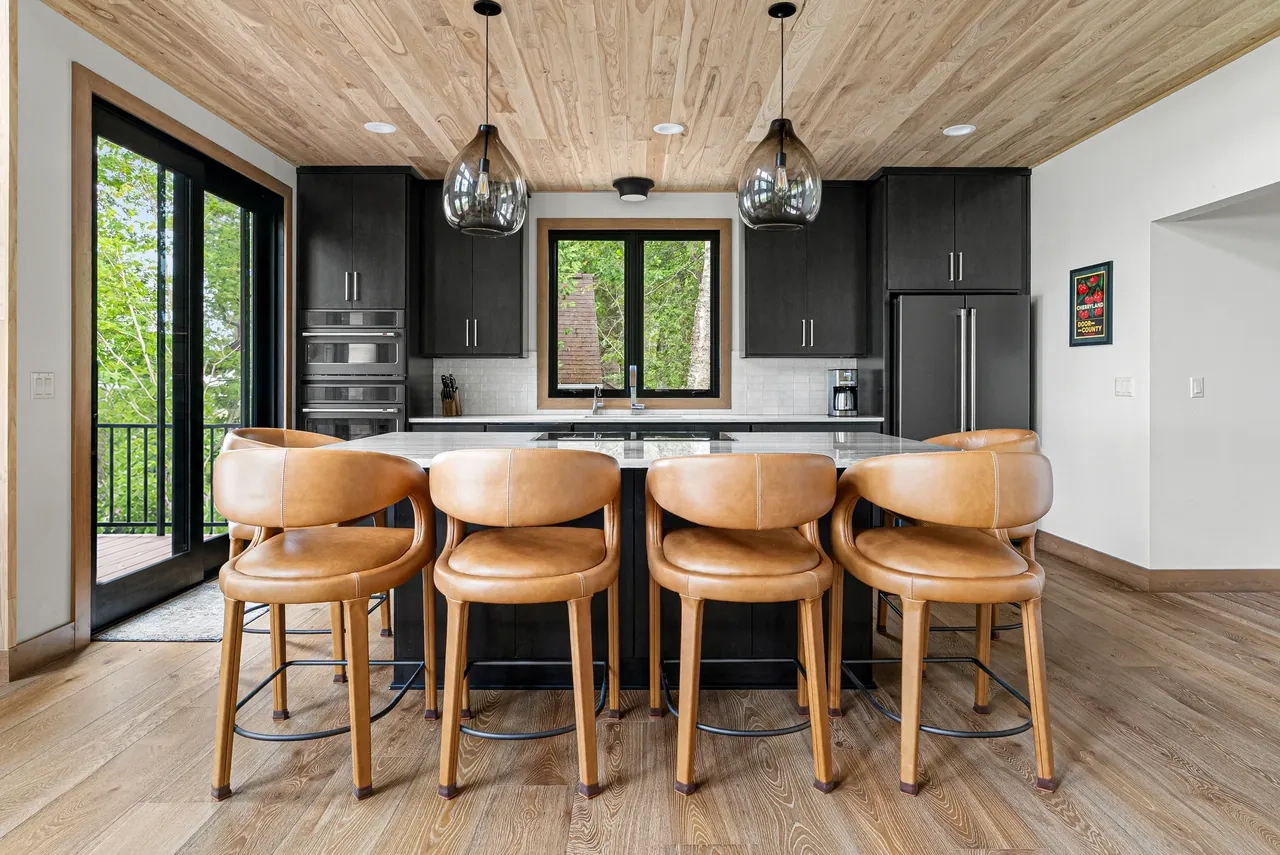 Kitchen with a wood ceiling, dark cabinetry and stools along the island